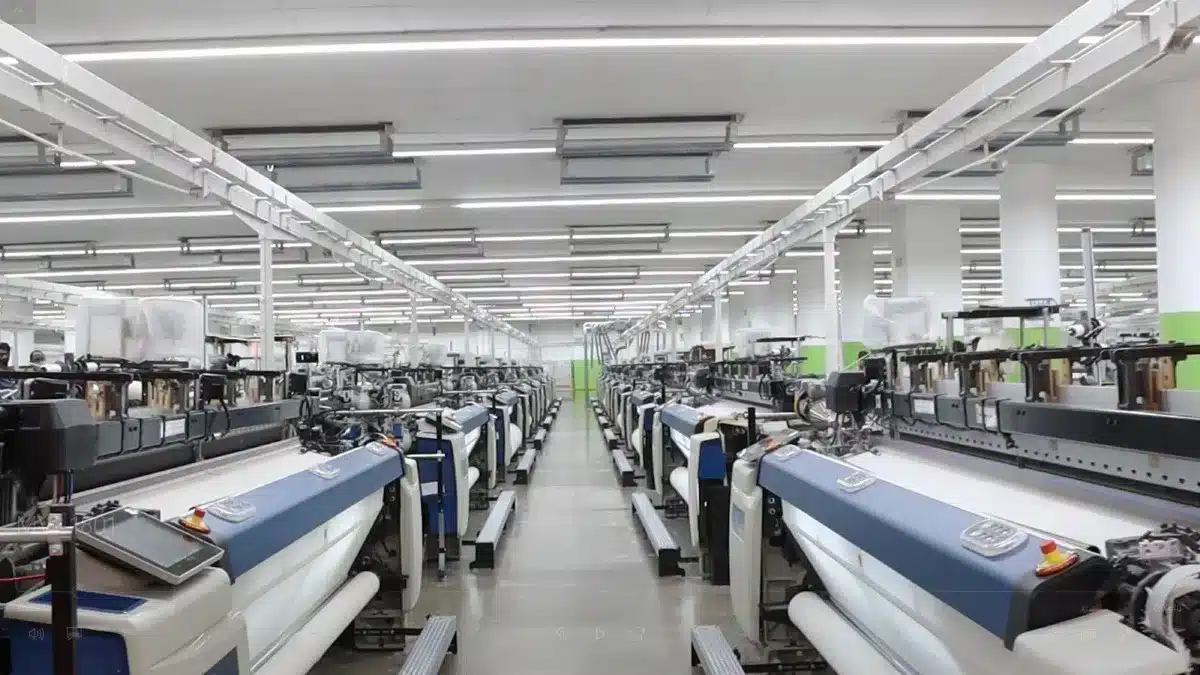 PET - Challenge Rows of textile machines in a brightly lit modern factory.
