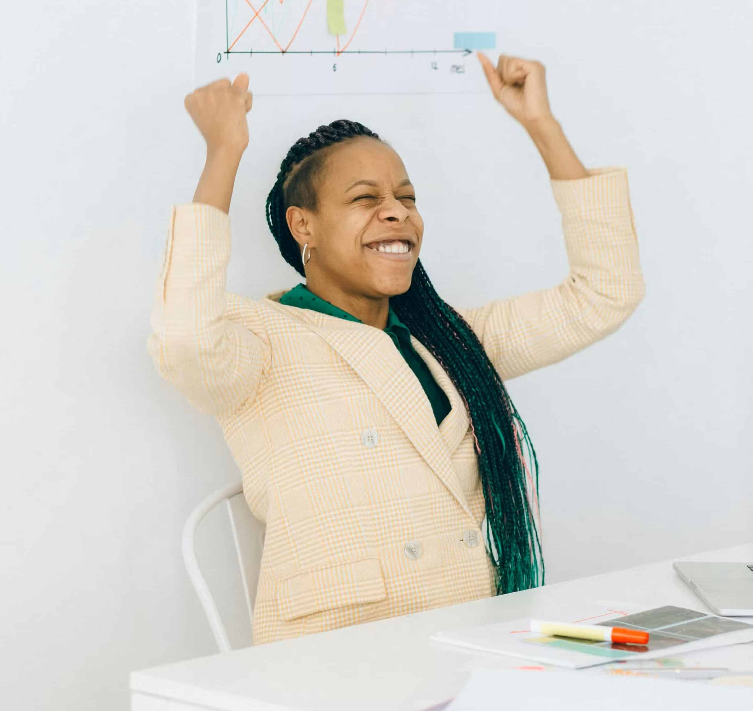 Why should you care Smiling person in a suit raising arms in celebration at a desk with papers and a chart in the background.